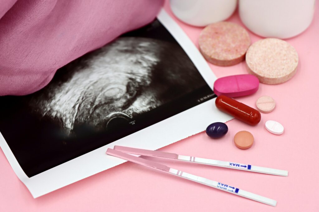pexels-photo-29027953-29027953 A closeup of pregnancy tests and an ultrasound with supplements on a pink background.