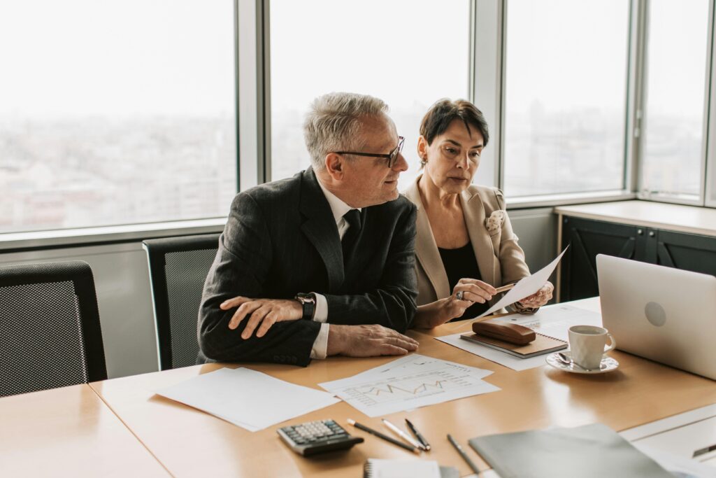 pexels-photo-7433826-7433826 Two business professionals analyzing financial papers in a modern office setting.